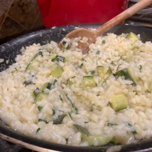 Diced Zucchini folded into creamy risotto with wooden spoon