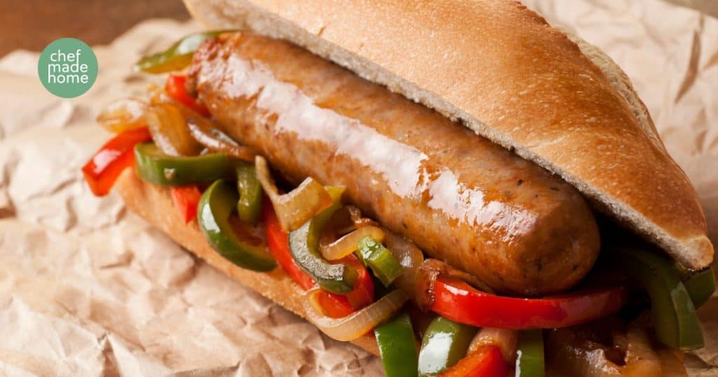 Smoked Bratwurst on a bed of peppers and onions inside a hoagie roll
